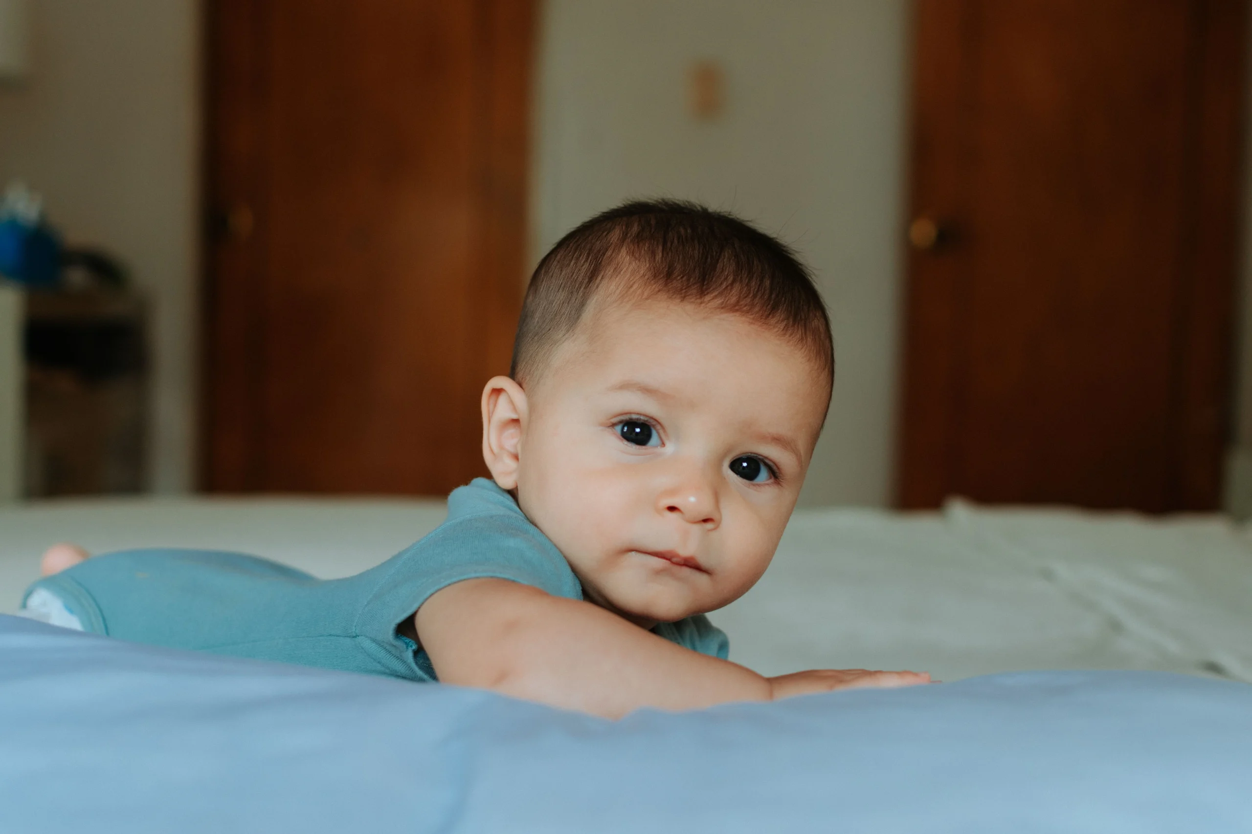 Baby practicing supervised tummy time on a play mat while reaching for a colorful toy, illustrating baby movement development.